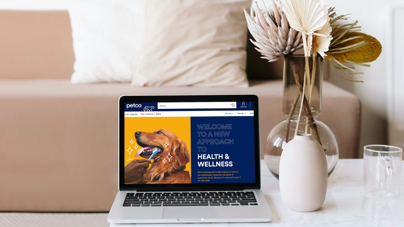 Laptop computer showing the Petco website with a picture of a drooling dog and the words "Health & Wellness" on the screen